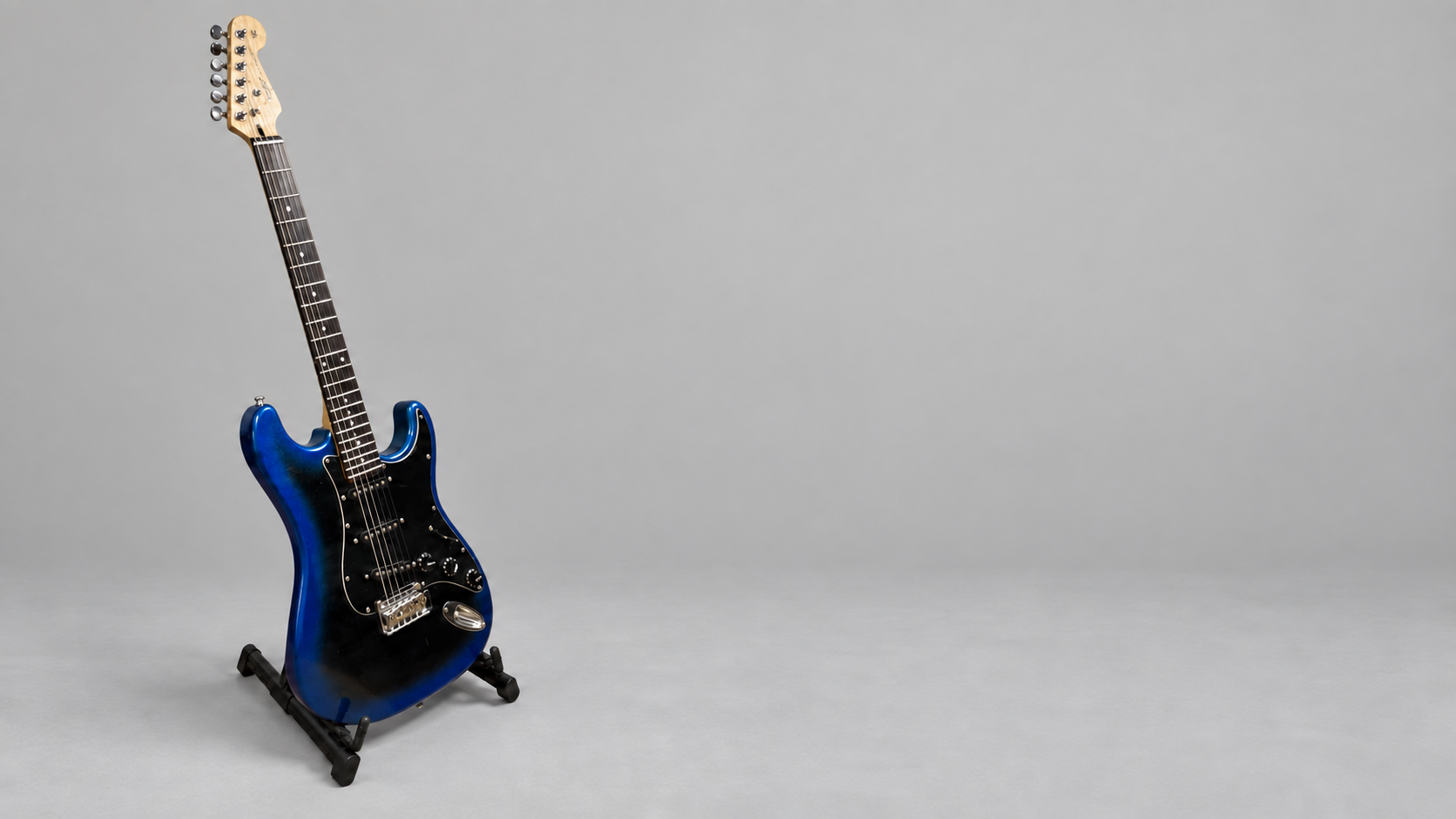 Синий Stratocaster на стойке в светло-серой студии